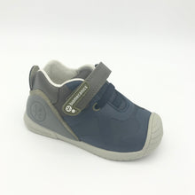 Load image into Gallery viewer, A navy and khaki colored pair of boys' sneakers with a single velcro fastening and a logo on the heel.