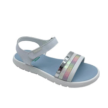Load image into Gallery viewer, A children's flat sandal with a light blue footbed, white sole, and metallic silver straps, one of which features a holographic iridescent stripe.
