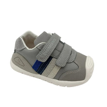 Load image into Gallery viewer, A grey toddler sneaker with hook-and-loop straps, a blue accent stripe, and a white sole, photographed on a light grey studio background.

